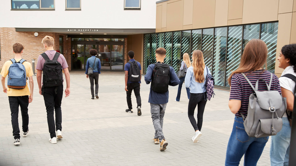Multiple high school student walking towards school building