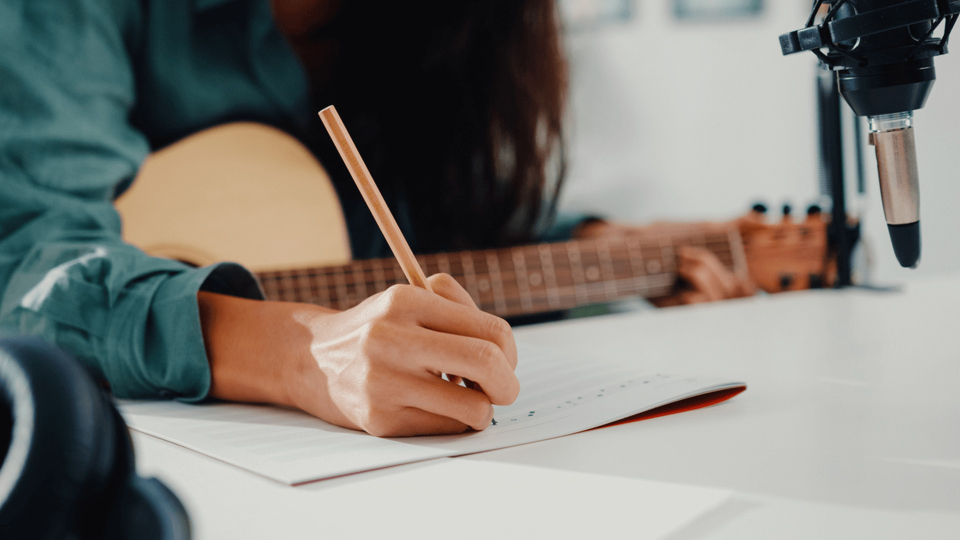 Female guitarist writing music on sheet of paper