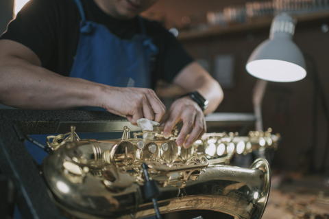 a repair technician works on a saxophone
