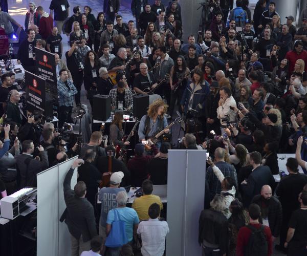 Aerial view of crowd gathered inside Anaheim Convention Center to watch performer play electric guitar.